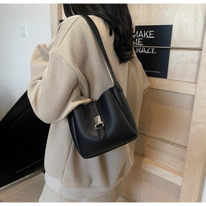 Macro detail of black pebbled leather bucket bag with silver metal buckle on model