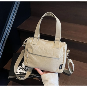 Gros plan du sac cabas plissé en nylon beige avec poignées tissées et étiquette