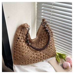 Detailed close-up of handmade hollow straw woven bag featuring vintage wooden bead handles