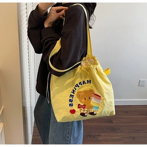 Detail of yellow drawstring tote bag with happiness letters and bear embroidery for women