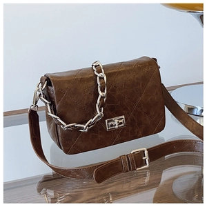 Macro shot of brown quilted leather bag with silver chain and metal turn-lock closure