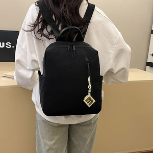 Detail of black leisure backpack with yellow pendant and side pockets on model