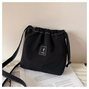 Detail of black drawstring crossbody bucket bag with white contrast stitching and logo