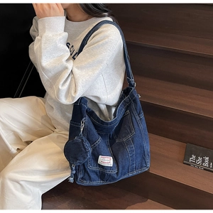 Détail d'un grand sac fourre-tout en denim bleu avec poches et petite pochette ronde