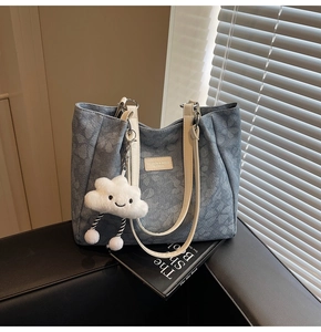 Détail du sac cabas floral bleu clair avec anses en cuir blanc et charme peluche