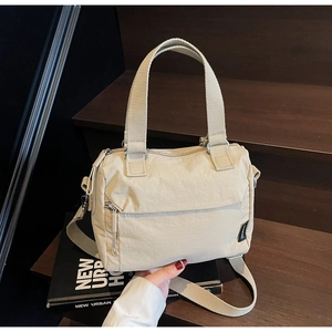 Détail du sac à main en nylon beige avec poignées larges et poche zippée externe