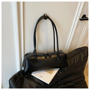 Detail view of black matte leather baguette bag with dual silver zippers and slim straps
