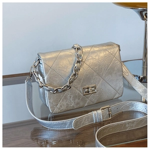 Macro shot of silver metallic quilted handbag with fold-over flap and twist-lock detail