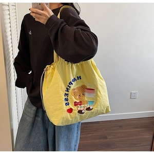 Detail of yellow drawstring tote bag with happiness embroidery and cartoon bear pattern