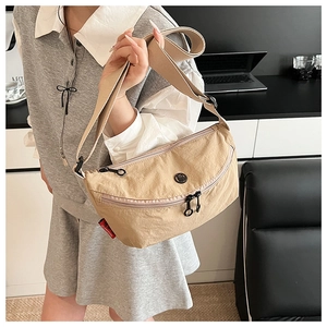 Detailed close-up of khaki nylon crossbody bag with dual zippers and adjustable strap