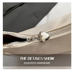 Close-up of heart-shaped silver zipper pull on beige canvas chic shoulder bag