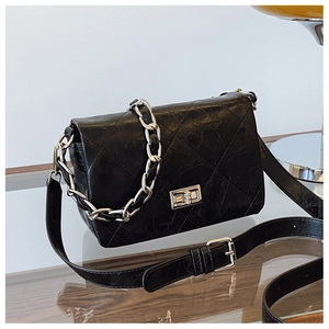 Detail of black quilted oil wax leather crossbody bag with silver twist lock and chain