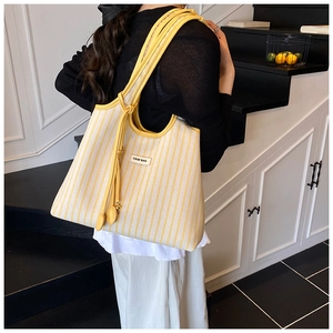 Detailansicht der gelb gestreiften Canvas-Tasche mit Lederriemen und Logo-Patch