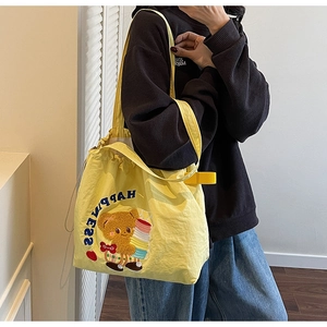 Detail of yellow canvas tote bag featuring an embroidered brown bear and HAPPINESS text
