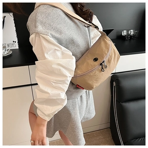 Detail showing the khaki nylon crossbody bag's smooth zipper and adjustable strap