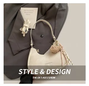 Detail of a beige half-moon hobo bag with a soft texture and a plush bear charm accessory