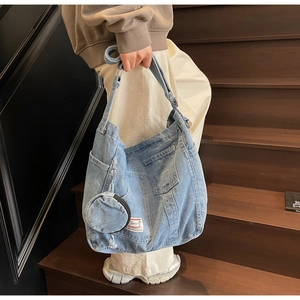 Détail du grand sac cabas en jean bleu clair avec pochette ronde sur escalier en bois