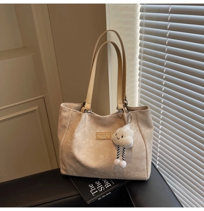 Détail du sac cabas crème avec motifs en relief et accessoire de charme nuage en peluche