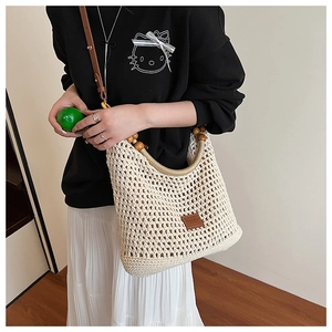 Detail of hand-woven straw tote with hollow mesh texture, wooden beads and leather strap
