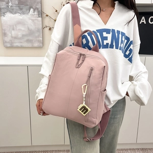 Detailed view of pale pink nylon backpack with side pockets and m-logo charm