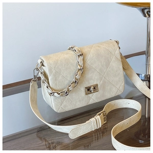 Detailed view of beige quilted leather crossbody bag with chain handle and gold clasp