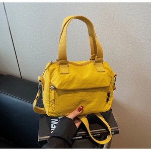 Détail du sac à main en toile jaune avec poignées en tissu et bandoulière réglable