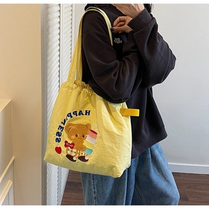 Detail view of yellow tote bag featuring Happiness letter print and cute bear embroidery