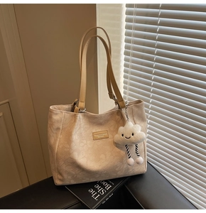 Détail du cabas beige avec texture florale, cuir synthétique et breloque nuage