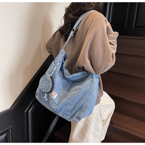 Détail d'un sac cabas en denim bleu avec poche frontale et porte-monnaie rond amovible
