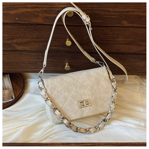 Detail of cream quilted crossbody bag featuring silver chain handle and metal twist lock