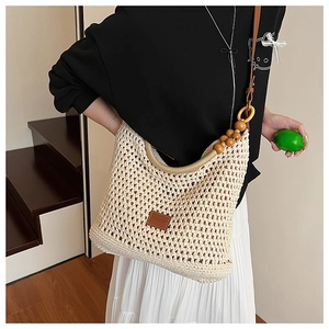 Close-up of beige crochet shoulder bag with wooden bead strap and leather label detail