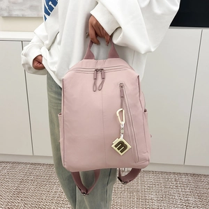 Pink nylon backpack detail showing dual zippers, front pocket and creative letter m charm