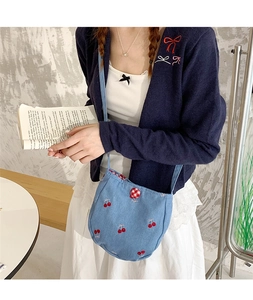 Détail du sac à bandoulière en jean avec broderie cerise et doublure à carreaux rouges