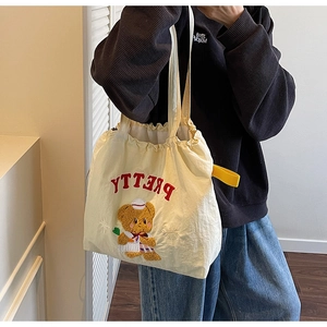 Detail of cream canvas tote bag featuring red PRETTY embroidery and plush bear design