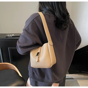 Détail du sac seau camel montrant le cuir grainé et la boucle décorative en métal argenté