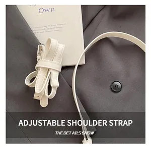 Close-up of cream faux leather adjustable shoulder strap with silver metal buckle detail