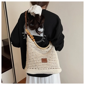 Detail of bohemian crochet tote with wooden beads and brown leather logo tag