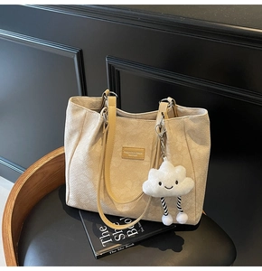 Détail du cabas en cuir beige texturé avec écusson logo et pendentif nuage doux