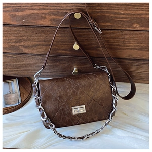 Detail view of the brown quilted crossbody bag with silver clasp and chain decoration