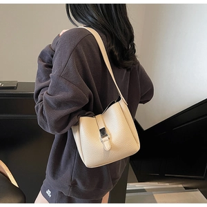 Détail du sac seau blanc cassé en cuir litchi avec boucle argentée et bandoulière réglable