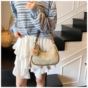 Detail of crescent shoulder bag with brown leather trim and cute plush bear charm