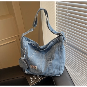 Vue macro du cabas en jean bleu avec étiquette vintage, large bandoulière et mini pochette