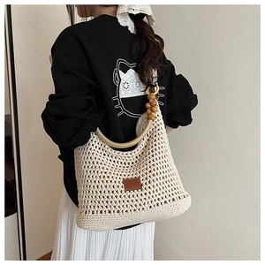Close-up of knit bucket bag featuring wooden bead handles and hollow mesh texture