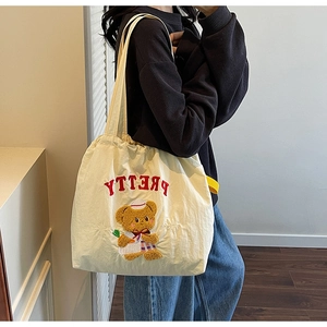Off-white canvas tote bag featuring embroidered plush bear and PRETTY lettering on shoulder