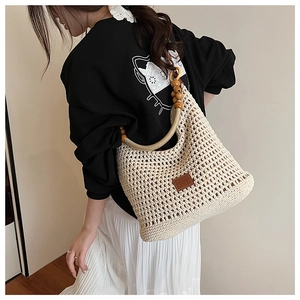 Detail of woven beach tote with intricate hollow knit patterns and vintage wooden bead handles