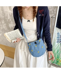 Vue détaillée du petit sac bandoulière en denim bleu avec broderies fleurs jaunes