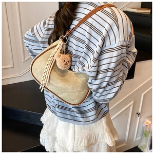 Detail of olive canvas hobo bag with brown leather trim and cute bear charm accessory