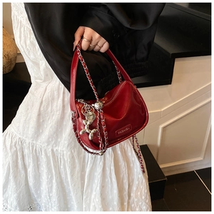 Detail of red patent leather handbag featuring a silver balloon dog charm and metal chain