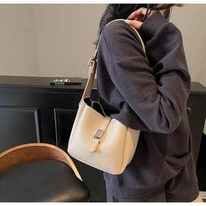 Détail du sac seau beige en cuir grainé avec fermoir argenté sur fond rétro