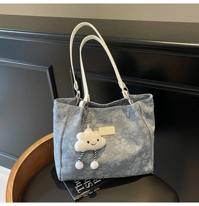 Détail d'un cabas à imprimé floral bleu avec anses blanches et breloque nuage en peluche